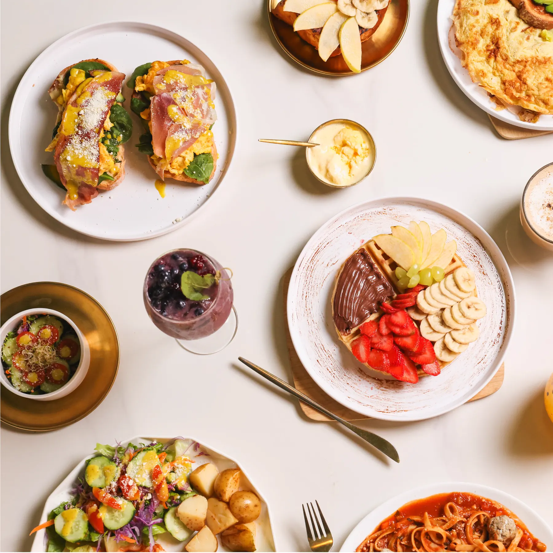 Una mesa de Amazónico vista desde arriba: toasts, waffle con fruta, ensalada, pasta, café y un drink de zarzamora