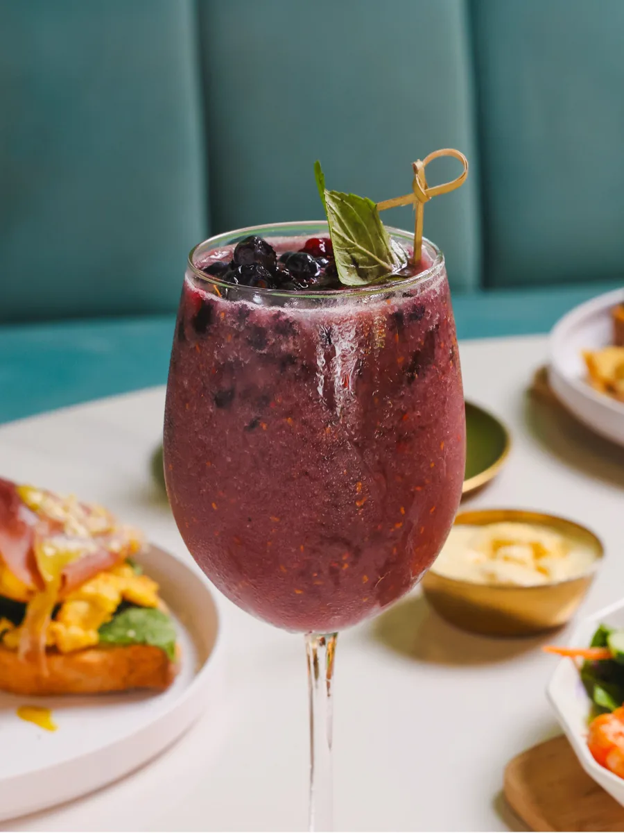 Blackberry Mojito en copa, con zarzamoras y hierbabuena, frente a un gabinete verde